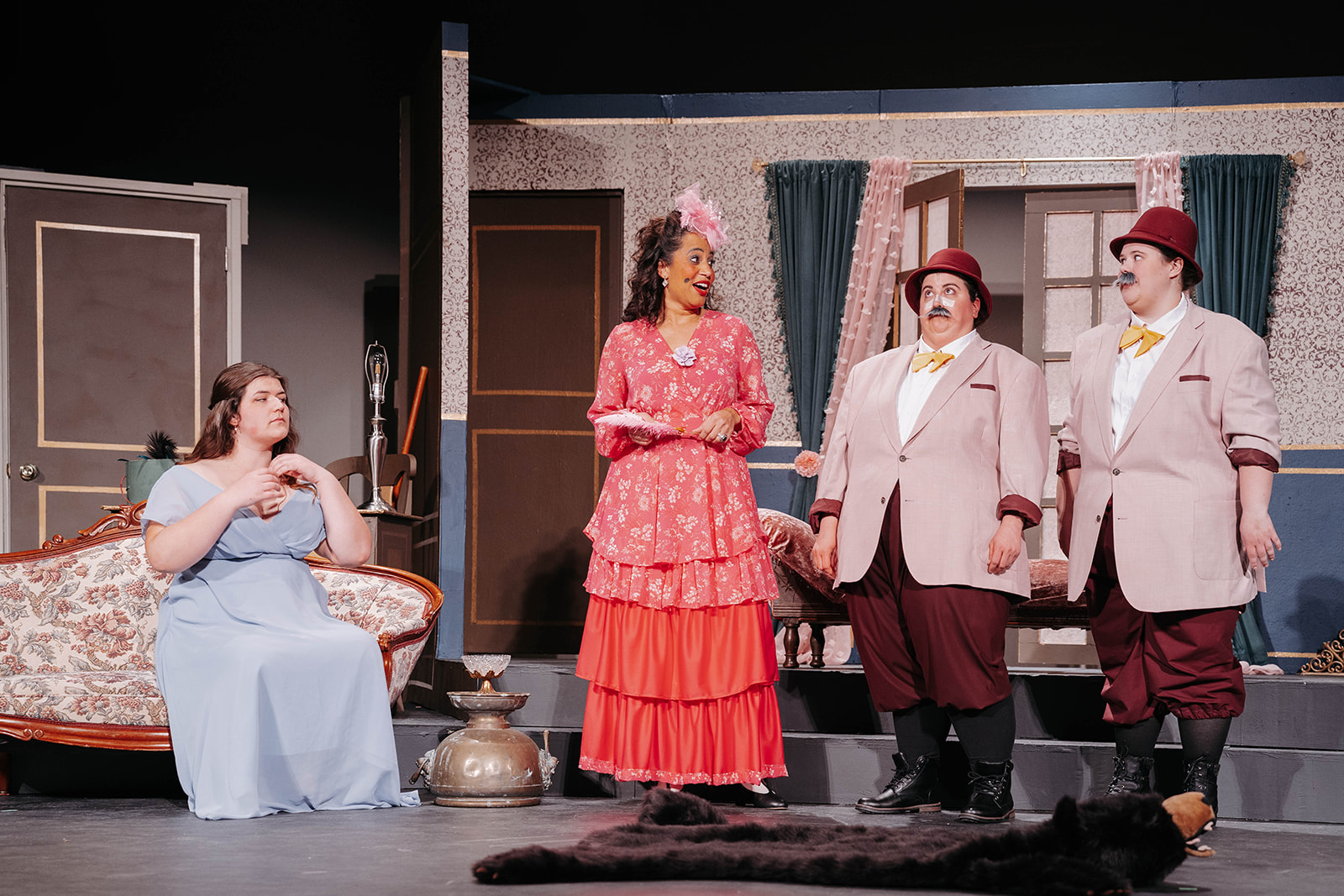 Rosetown Playhouse Wide stage shot showing performers in various period costumes including elaborate gowns, officials in beige suits, and characters in simpler period dress spread across the set.