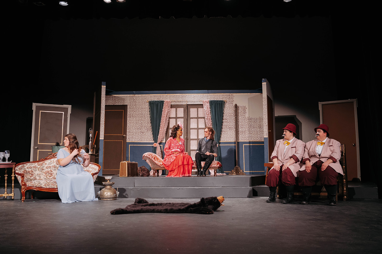 Rosetown Playhouse Wide angle of the stage showing multiple performers arranged in conversation, with the detailed interior set visible including wallpapered walls, curtains, and period furniture.