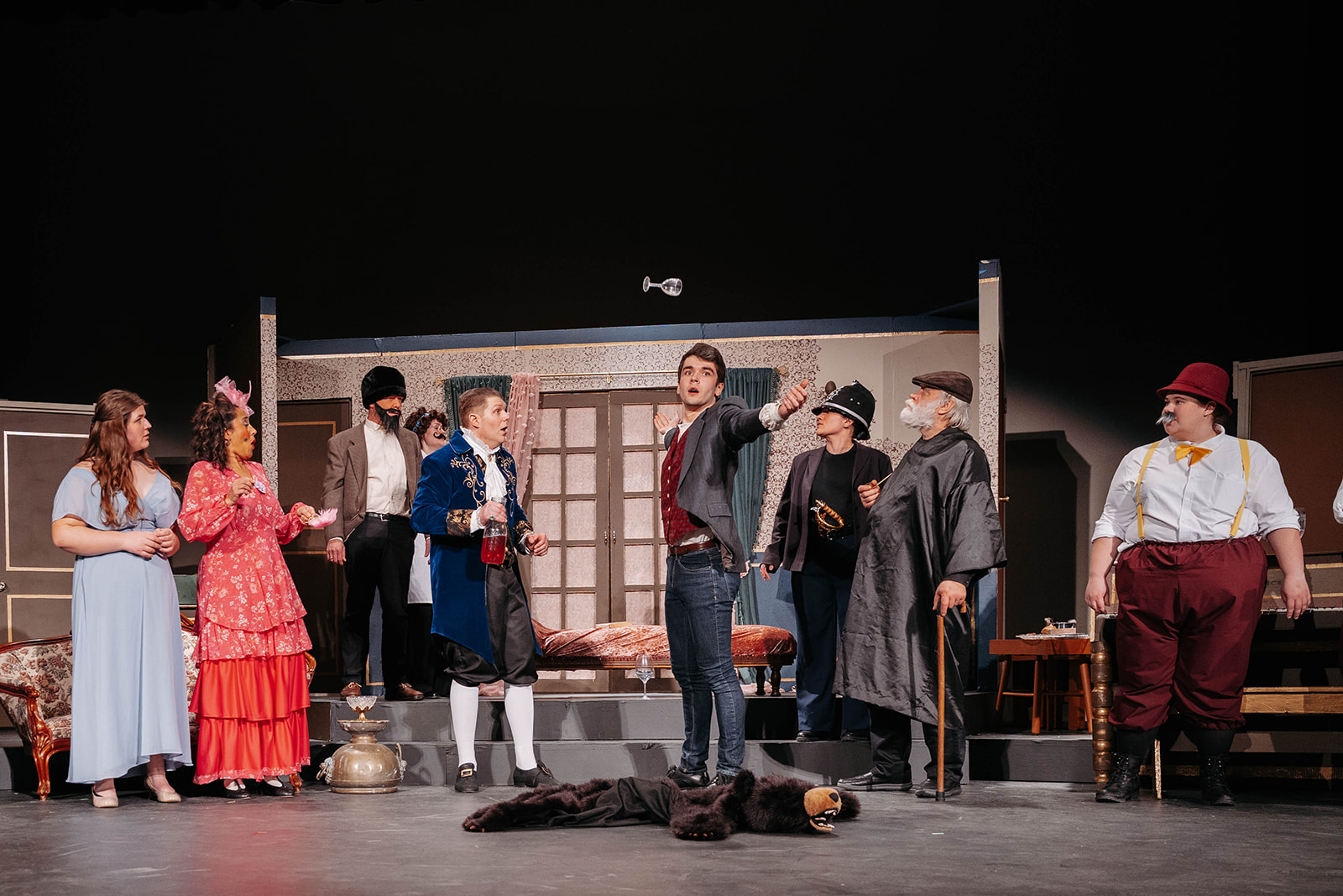 Rosetown Playhouse Ensemble scene with the full cast gathered on stage, including a performer gesturing dramatically while others react, with a prop key visible floating in the air.